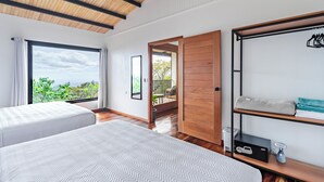 Een slaapkamer met twee bedden, een houten plafond, een groot raam met uitzicht en een balkon.