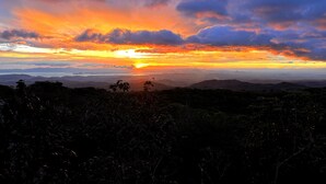 Een zonsondergang boven een bergachtig landschap, met een helder uitzicht op de horizon.