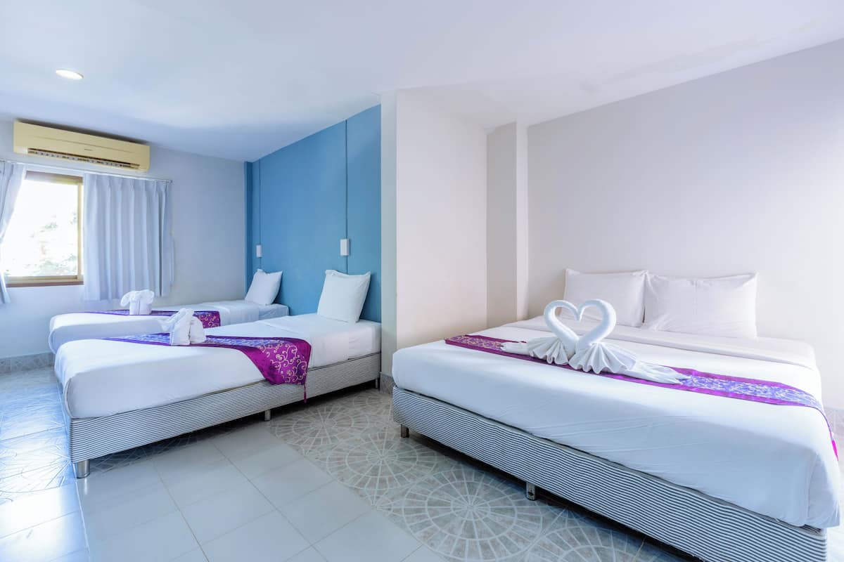 A hotel room with two beds, a large window with curtains, and a patterned floor.