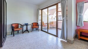 A spacious room with a large sliding glass door leading to an outdoor area, two wooden chairs, a small table, and a wooden bench. - Huahin Star Hotel (Hua Hin)