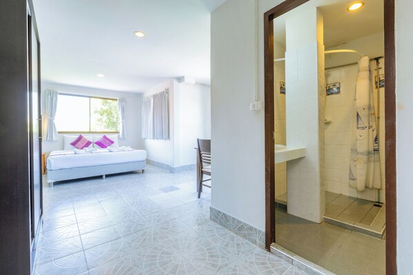 A hotel room with a bed, a shower area, and a view of the outdoors.