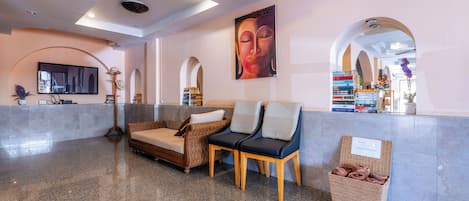 A lobby with a reception desk, seating area, and a wall-mounted television.