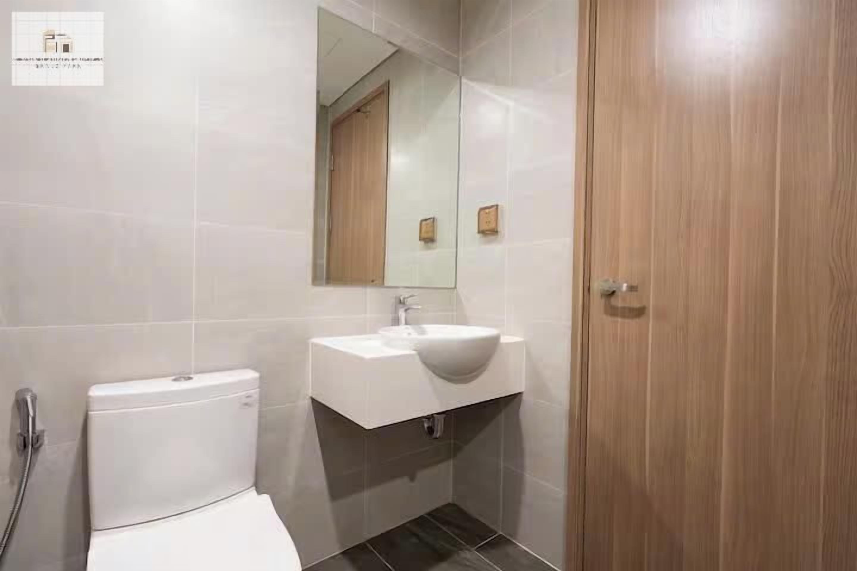 A modern bathroom with a toilet, sink, and mirror.
