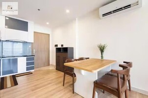 A modern kitchen with a built-in stove, a wooden dining table with four chairs, and a small potted plant on the table.