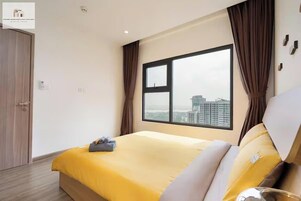 Ein Hotelzimmer mit einem großen Bett, Blick auf die Stadt und einer Tür.