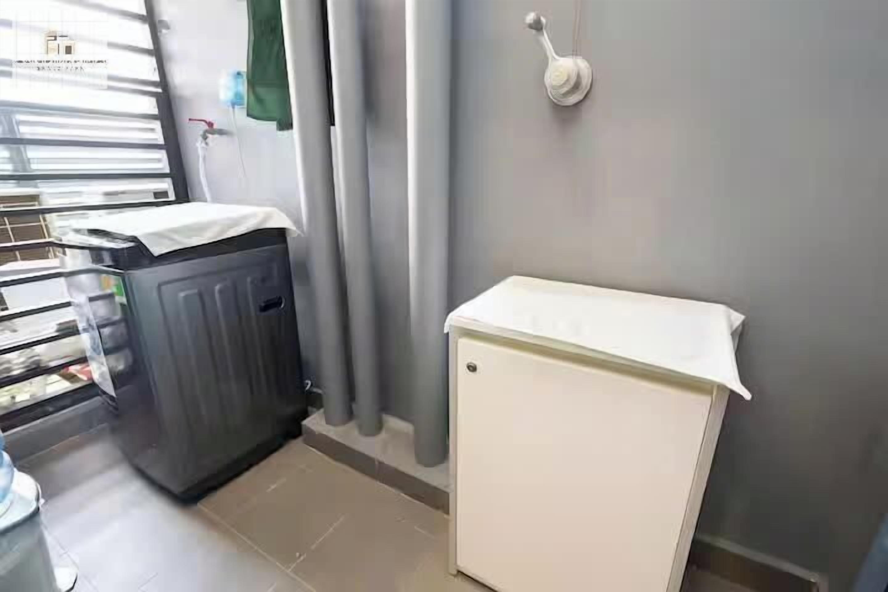 Una habitación pequeña con un refrigerador blanco, un mueble de color oscuro y una ventana con persianas.
