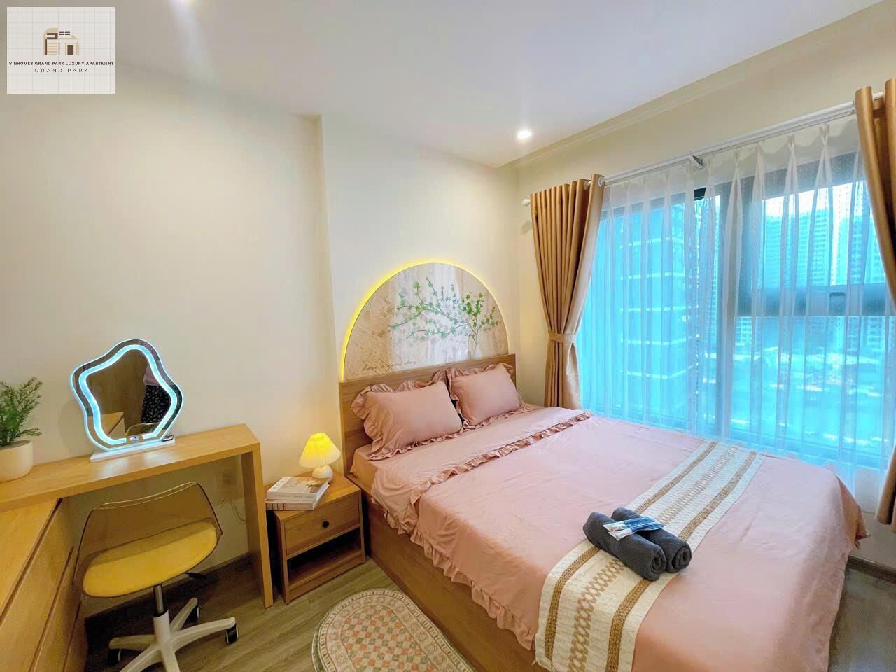 A bedroom with a bed, bedside table, lamp, chair, and a desk with a mirror.