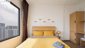 Quarto de hotel com uma cama grande, vista da cidade e um guarda-roupa.