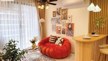 Una sala de estar moderna con un sillón informal rojo, una mesita de centro redonda y una pequeña zona de bar.