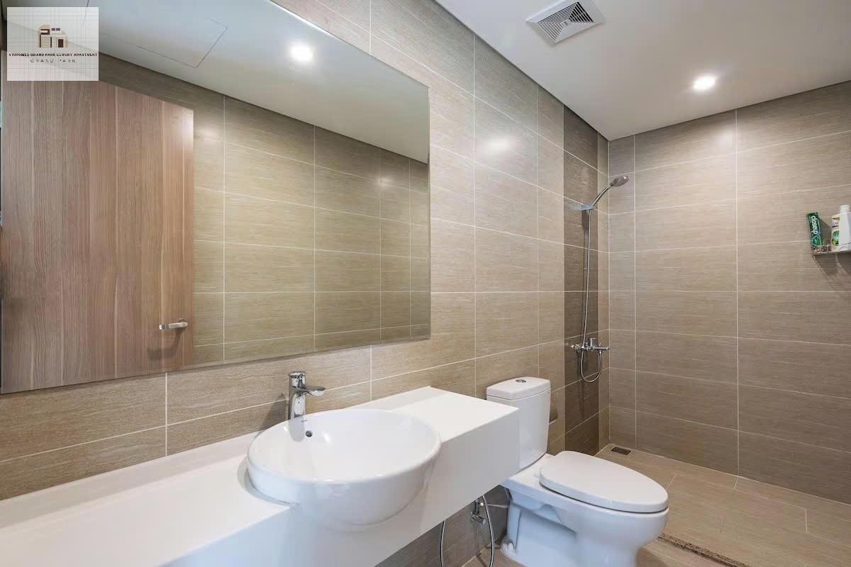 Un baño moderno con un espejo grande, un lavabo, un inodoro y una ducha.