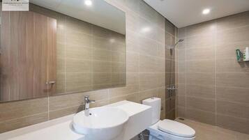 Un baño moderno con un espejo grande, un lavabo, un inodoro y una ducha.