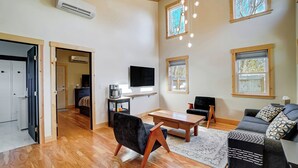 Una sala de estar moderna con techo de madera, televisor de pantalla plana, mesa de centro y sofá.