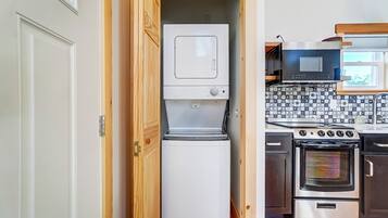 Een kleine keuken met een witte koelkast, een magnetron en een fornuis.