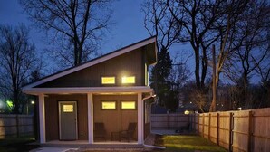 Una casa moderna con terraza, una fogata y asientos al aire libre.