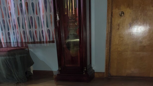 Una habitación con cama, puerta de madera, alfombra estampada y espejo.