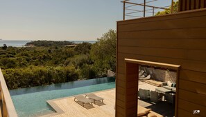 A modern outdoor pool area with lounge chairs and a view of the sea. - Palombaggia - Villa "SUNTUOSA": Where Luxury Meets Privacy (Porto-Vecchio)