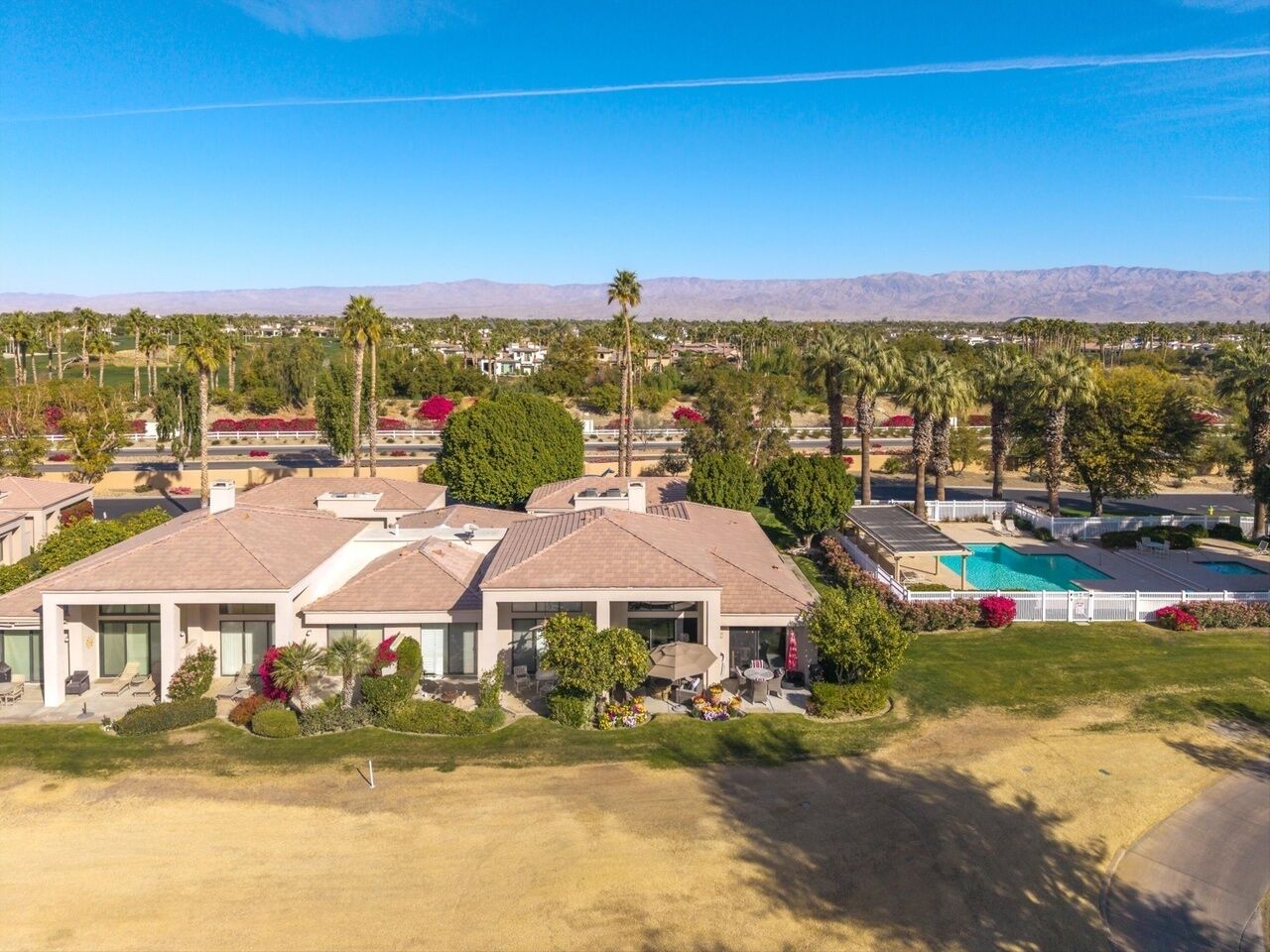 A residential area with multiple houses, a swimming pool, and a clear view of distant mountains.
