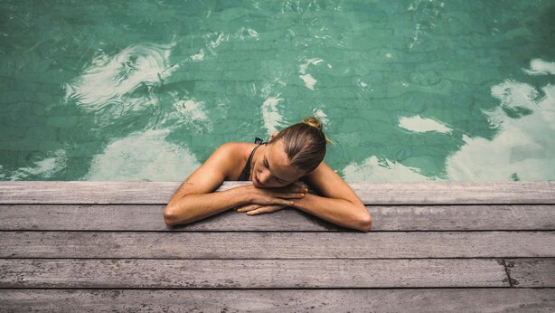 A person resting by a pool with a wooden deck. - iSuite by Ekosistem (Keroboken Kelod)