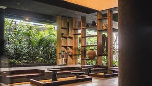 A modern interior with wooden shelves displaying pottery, a central wooden structure, and a view of lush greenery outside. - iSuite by Ekosistem (Keroboken Kelod)