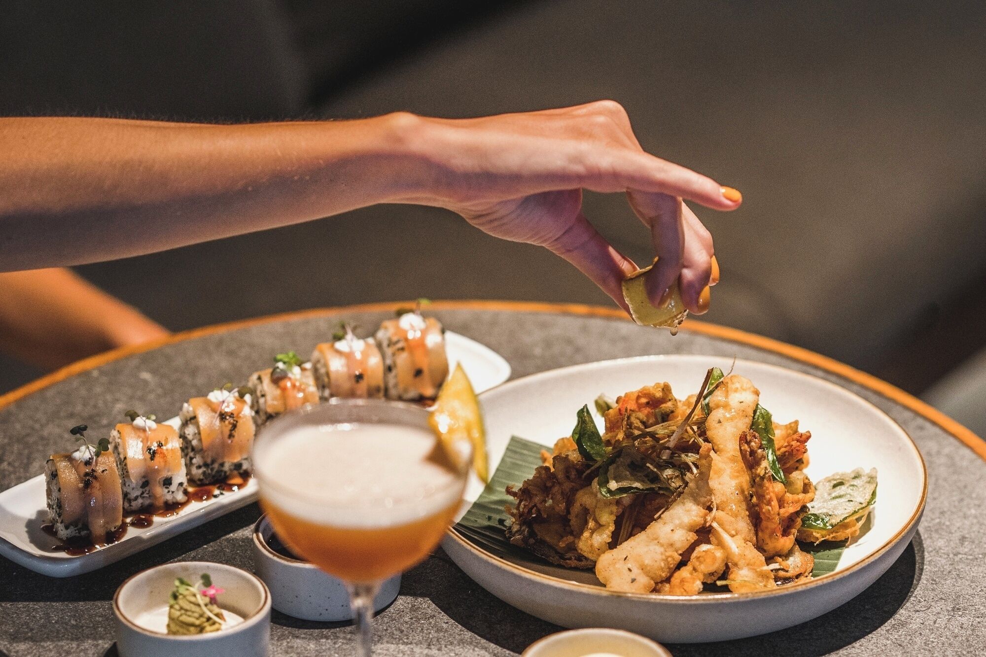 Un plat de sushi, un got de cervesa i un plat de menjar fregit.