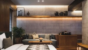 A modern bedroom with a bed, a sofa, a coffee table, and a small wooden side table. - iSuite by Ekosistem (Keroboken Kelod)