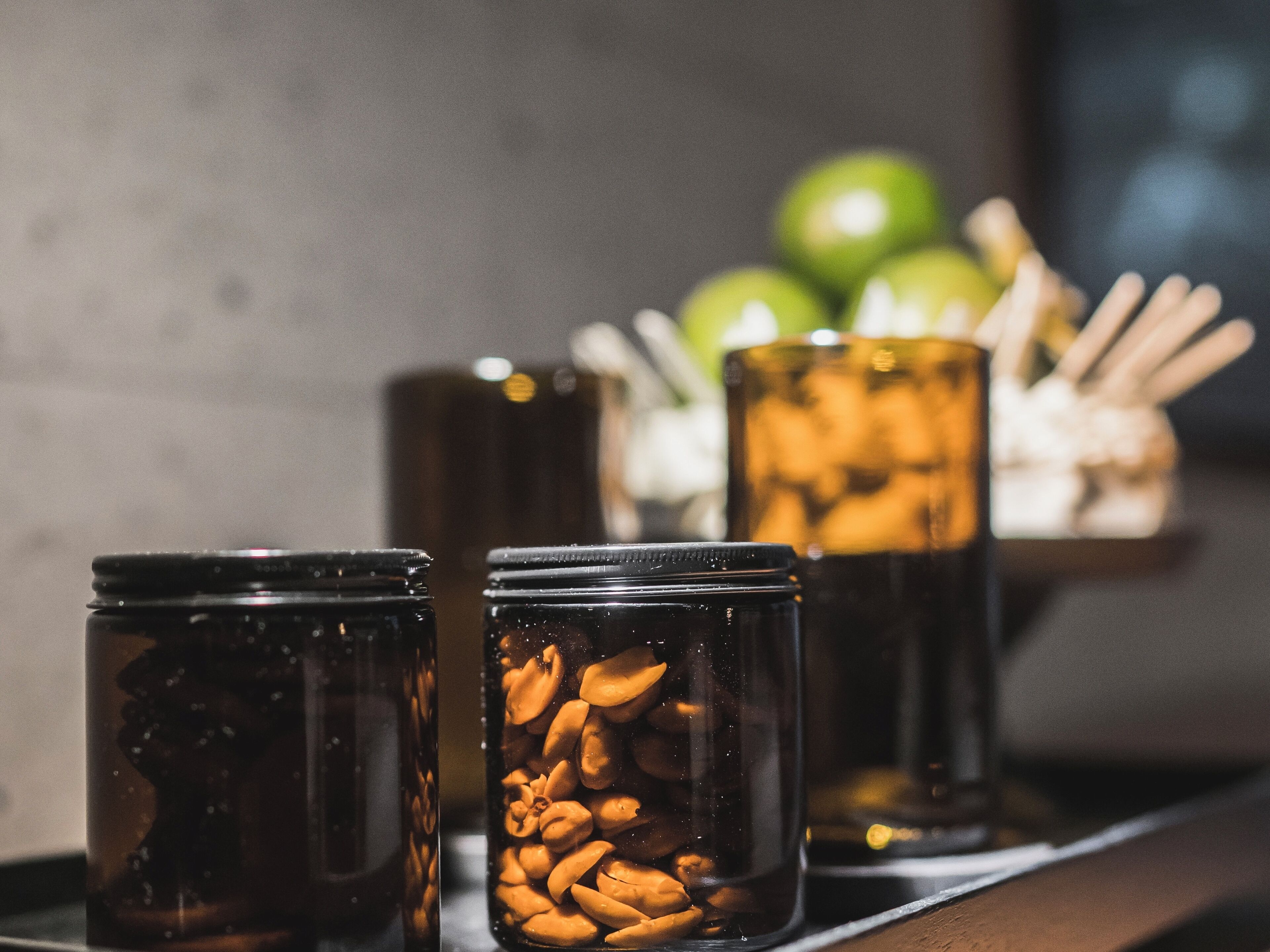 Three glass jars filled with nuts on a wooden surface.