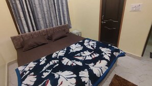 Une chambre à coucher avec un lit, une fenêtre avec des rideaux, une porte et une petite table de chevet.