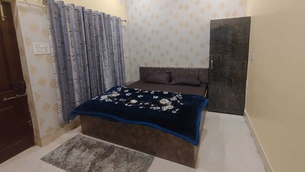 Une chambre à coucher avec un lit, une armoire de couleur sombre, un rideau à motifs et un papier peint à motifs.