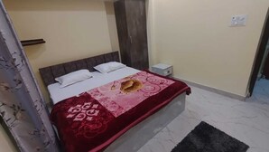 Une chambre à coucher avec un lit, une table de chevet, une armoire et une porte menant à la salle de bain.