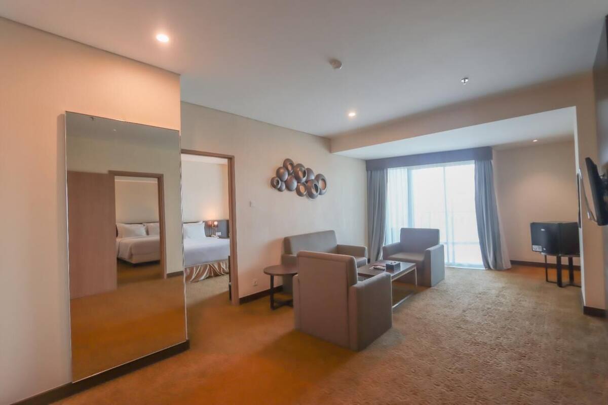 Une chambre d’hôtel avec un grand miroir, un canapé, une table basse et un téléviseur.