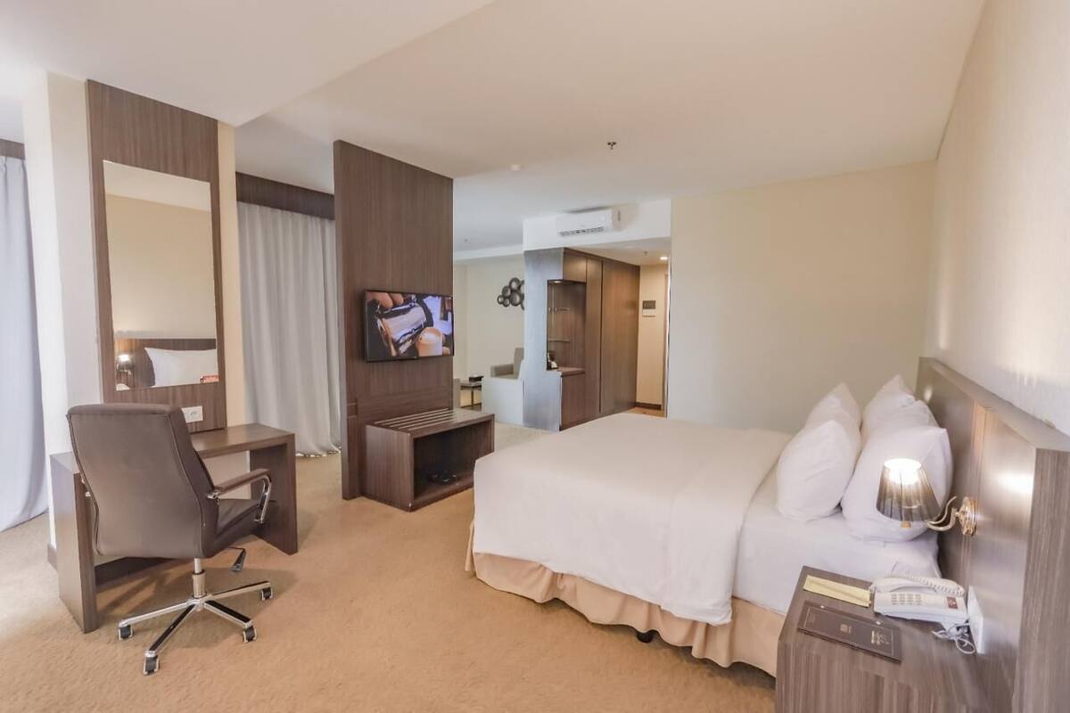 Une chambre d’hôtel comprenant un lit, un bureau, une chaise, une télévision et une armoire.