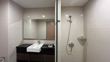 Un baño moderno con mampara de vidrio, lavamanos blanco, espejo y zona de ducha.