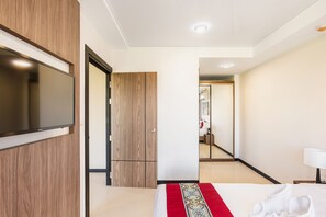 A hotel room with a bed, a TV mounted on the wall, a wardrobe, and a mirror. - One bedroom Condo in Naiharn P209 (Rawai)
