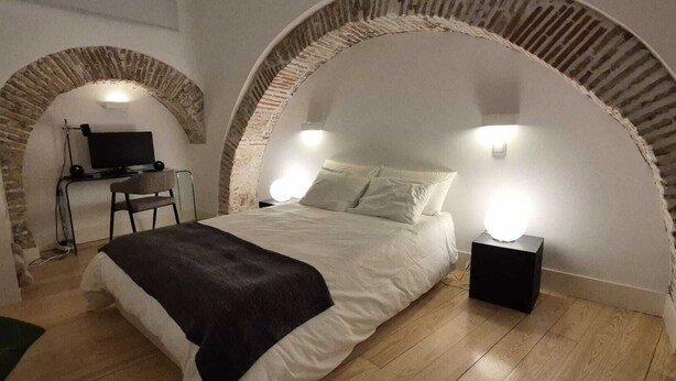 A bedroom with a bed, a desk, and two wall-mounted lights. - Alfama S Loft (Lisboa)