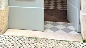 A light blue door with a barred window, leading to a staircase with a checkered floor. - Alfama S Loft (Lisboa)
