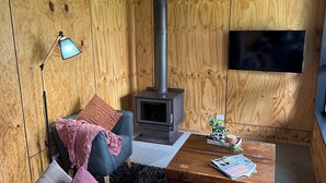 Ein gemütliches Wohnzimmer mit einer Couch, einem Couchtisch, einem Fernseher und einem Kaminofen.