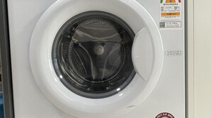 A white LG TROMM DD Inverter 9kg front-loading washing machine with a digital display, control panel, and a safety rating sticker.