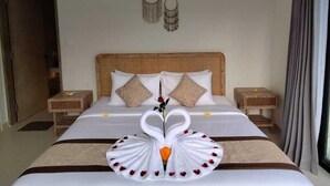 Een hotelkamer met een groot bed, twee nachtkastjes, een houten hoofdeinde en een decoratieve zwaan als middelpunt.