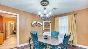 Ein Esszimmer mit Holztisch und -stühlen, einer Kronleuchter und einem gemusterten Teppich.