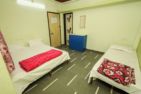 A room with two beds, a desk, and a door.