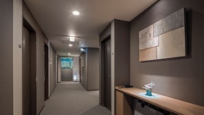 A hotel corridor with a wooden desk, a wall-mounted artwork, and a ceiling light. - HOTEL ROUTE-INN Grand NAGOYA FUJIGAOKA EKIMAE (Nagoya)