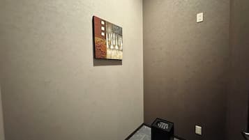 Un pasillo con pared texturizada, un pequeño cuadro y un altavoz negro.