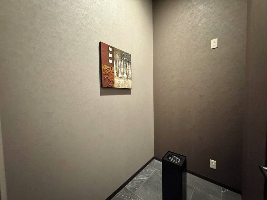 Un pasillo con pared texturizada, un pequeño cuadro y un altavoz negro.