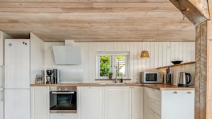 A compact kitchen with white cabinetry, a built-in oven, a microwave, and a coffee maker. - "Shaya" - 325m from the sea by Interhome (Allingåbro)