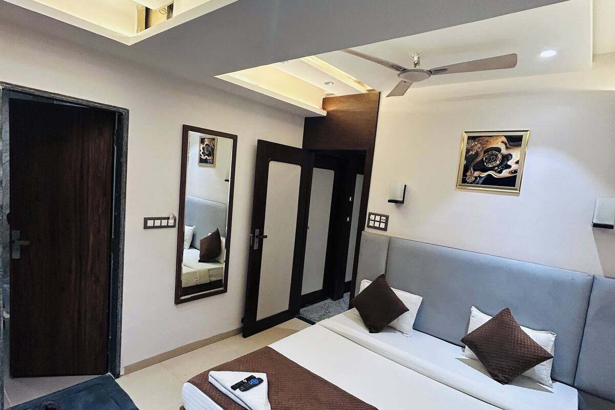 A modern hotel room with a large bed, a ceiling fan, and a small desk area.