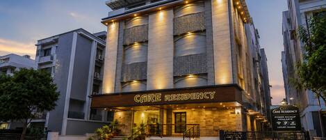 A multi-story building with a sign reading 'CARE RESIDENCY' and a sign indicating 'LUXURY ROOMS' and 'POWER BACKUP AVAILABLE'.