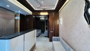 A modern lobby with a reception desk, seating area, and a ceiling fan. - Hotel Care Residency (Indore)