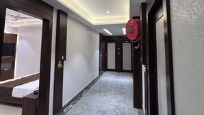 A hallway with a marble floor, recessed ceiling lighting, and doors leading to rooms. - Hotel Care Residency (Indore)