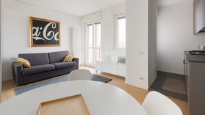 En moderne stue med sofa, spisebord og et køkkenområde.