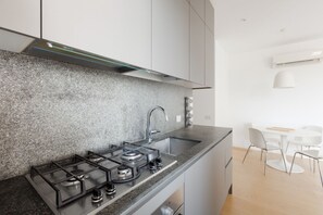 Una cocina moderna con estufa a gas, lavamanos y muebles de cocina blancos.